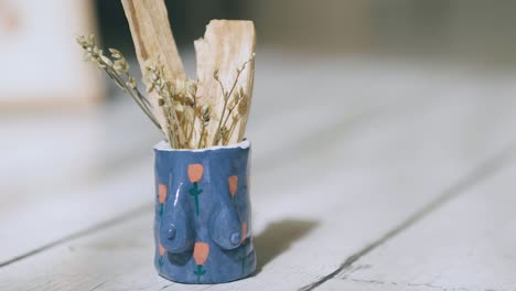 blue feminist mini jar with painted little roses, with holy pole and little yellow flowers inside