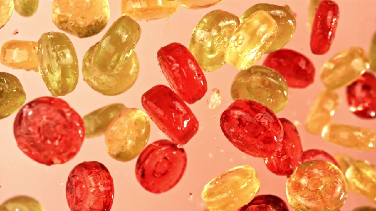 Caramelle colorate che galleggiano al rallentatore su uno sfondo rosa