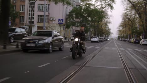 Muscular-man-with-orange-iroquois-rides-a-bike-in-the-city-in-the-dusk