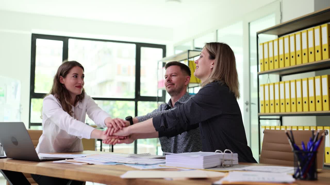 Colleghi si tengono per mano in un gesto di team building in ufficio