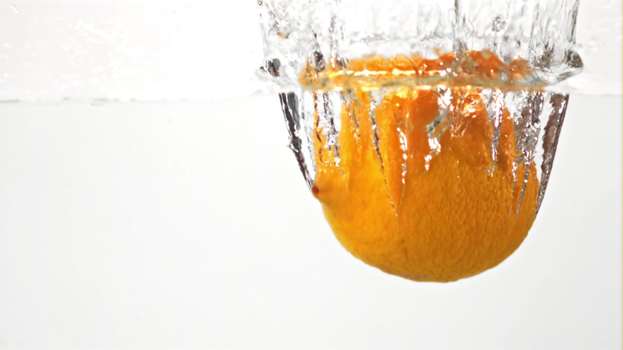 Limone fresco che cade e schizza in acqua limpida al rallentatore