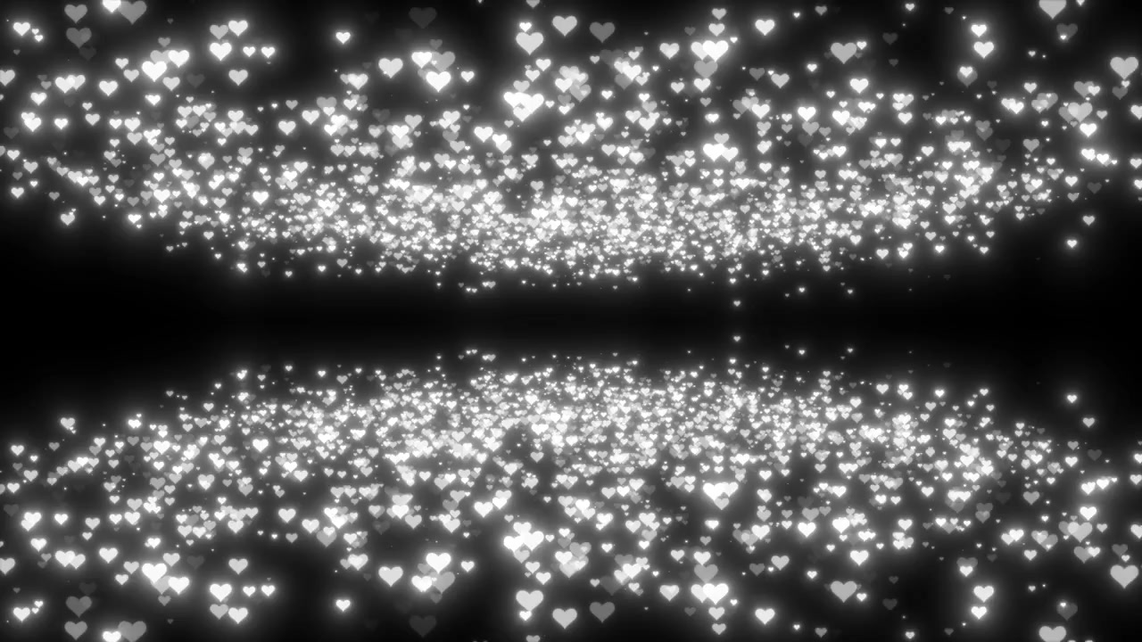 Particelle a forma di cuore bianco luminoso che fluttuano su sfondo nero