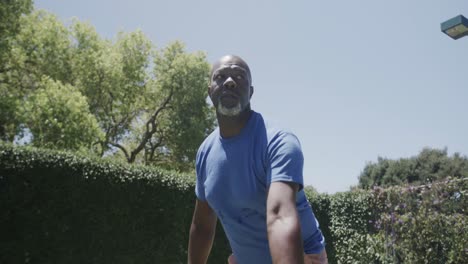 happy senior african american man playing tennis at tennis court in slow motion