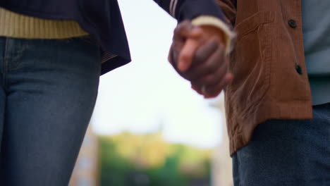 pareja de manos juntas caminando en la calle desenfocada cielo de fondo de primer plano