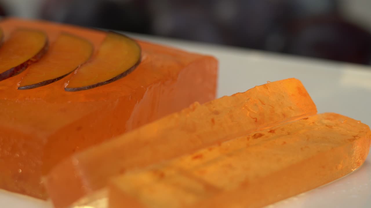 Close up of marmalade rotate on tray on background of ripe plums. Turkish delight. Fruit dessert, sweetness, jujube.