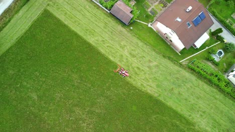 lawnmower tractor cutting grass in straight lines beside urbane settlement