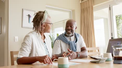 African-american-senior-couple-doing-paperwork-using-laptop-at-home,-slow-motion