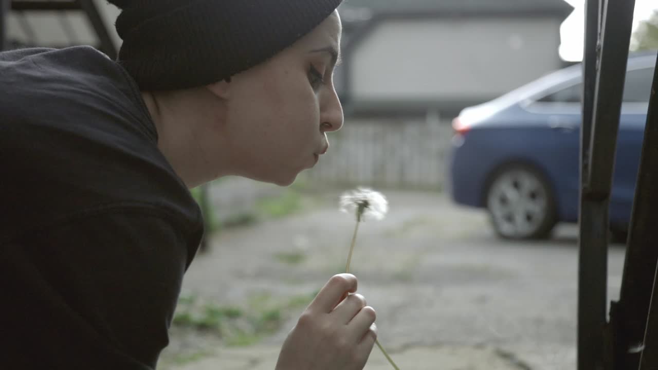 A Young Caucasian Man Picking Up And And Blowing Dandelion Seeds. - close up shot