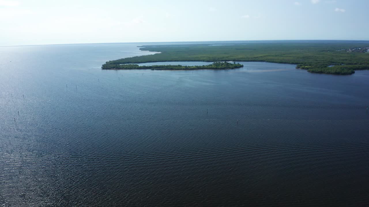 Águas abertas da baía se estendem em direção a ilhas de mangue baixas e pântanos costeiros rasos na Florida Bay, perto do Parque Nacional de Everglades, transmitindo uma atmosfera calma e remota, moldada pelo vento e pela maré