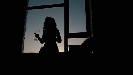 Silhouette-Einer-Dame,-Die-Bei-Sonnenuntergang-Mit-Weinglas-Tanzt