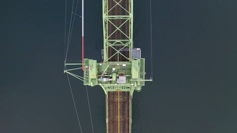 aerial view of vehicles driving across a green truss bridge over water