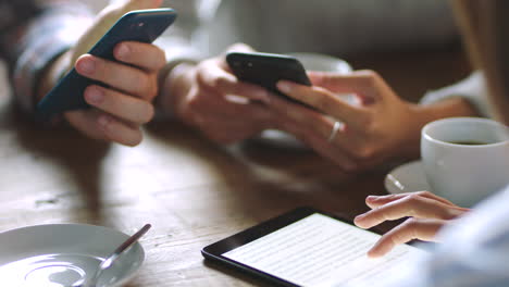 personas que usan teléfonos inteligentes y tabletas en una cafetería