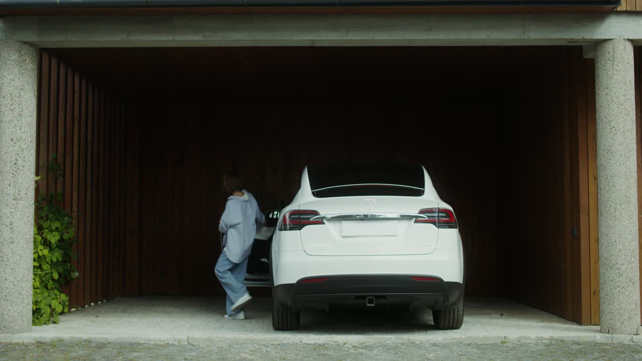 차고 에서 전기 자동차 를 충전 하는 여자