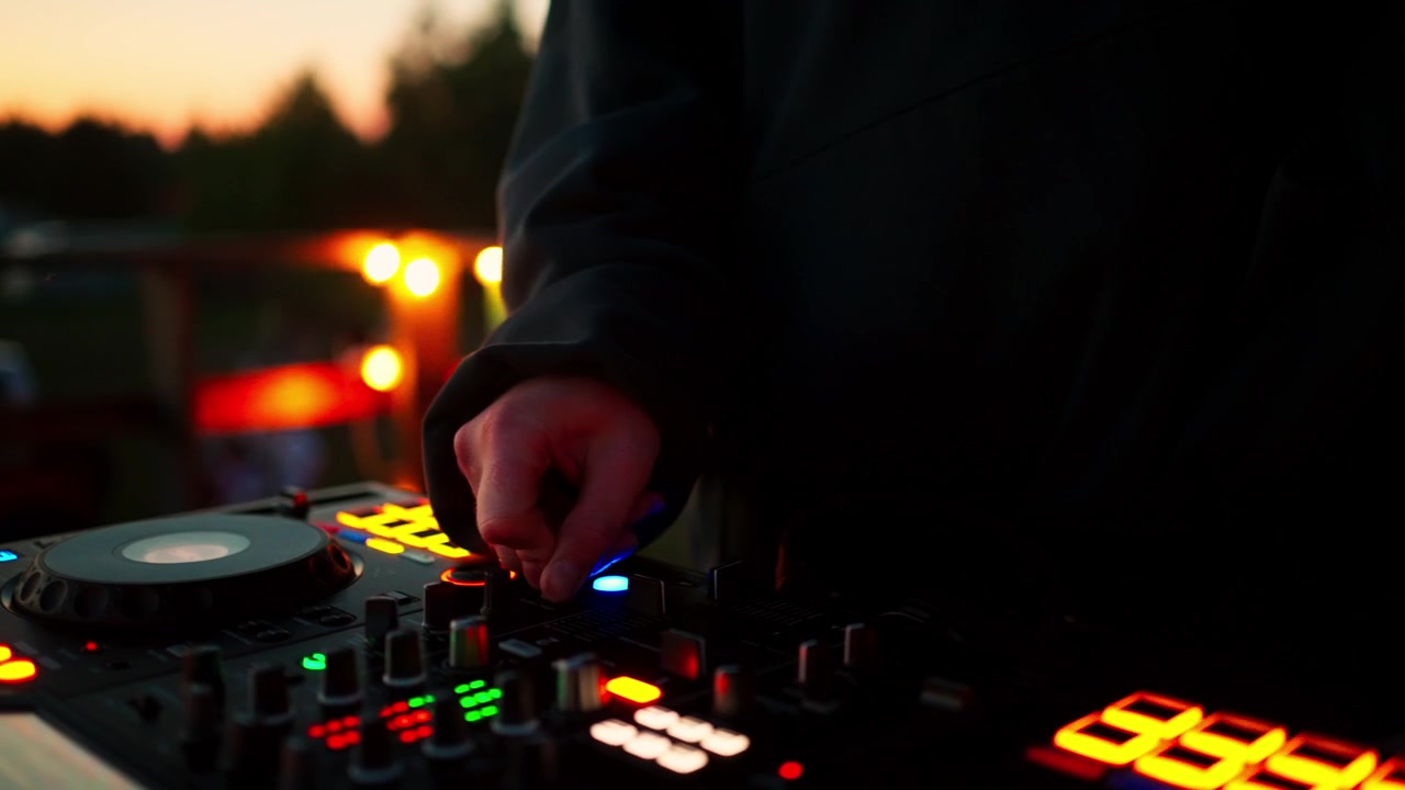 DJ che mixa musica su console a una festa all'aperto al tramonto