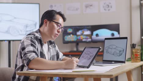 side view of asian male having a headache while drawing new car design concept on a tablet in the studio with tv and computers display 3d electric car model