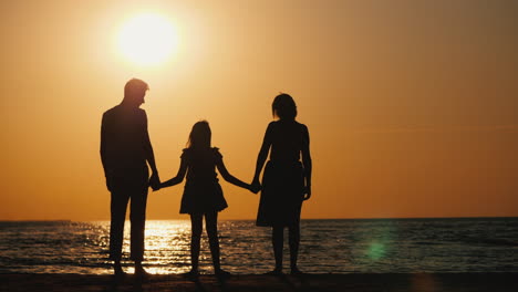 family with a child goes to the sea at sunset