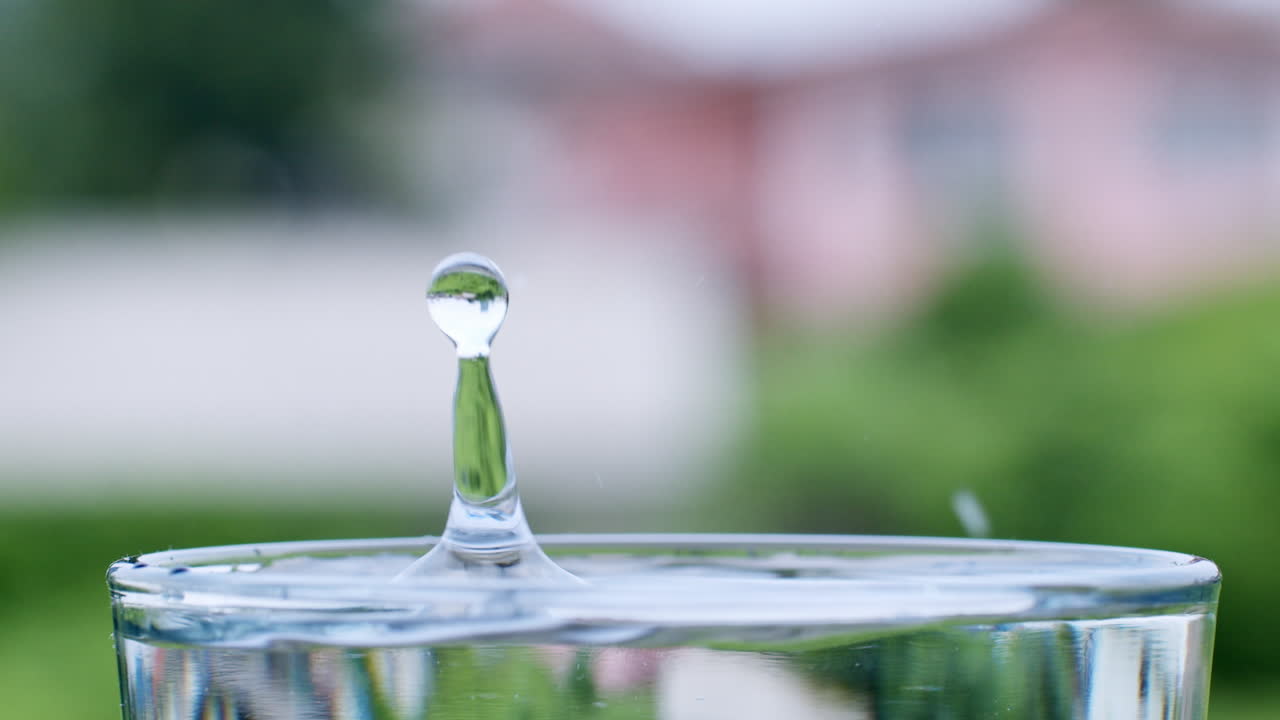 un vaso lleno de agua hasta el borde con gotas de agua salpicando y creando ondas y ondas en él
