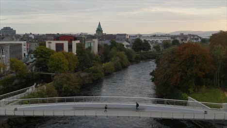 people waking on a pedestrian bridge in galway city