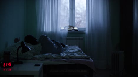 man sleeping in a dark bedroom