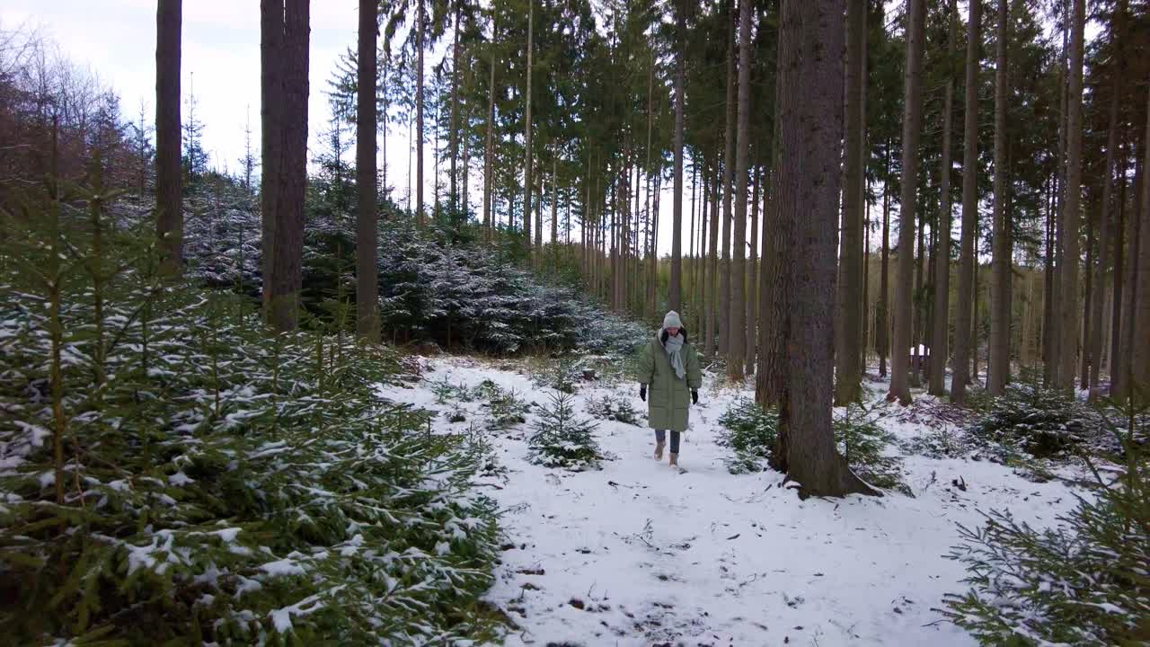 chica con ropa de invierno camina por un bosque nevado en cámara lenta a la cámara