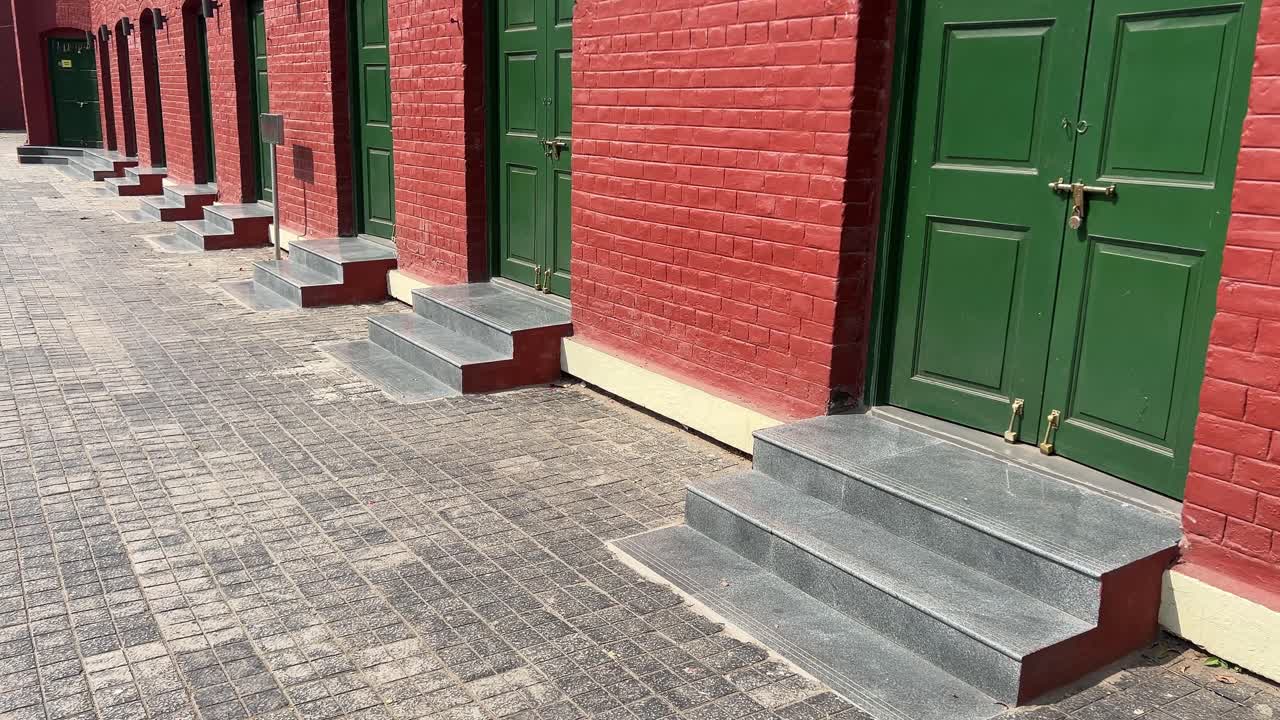 View of old textured green wooden doors with red wall in Alipore Jail Museum built during British East India Company era at Kolkata, India.
