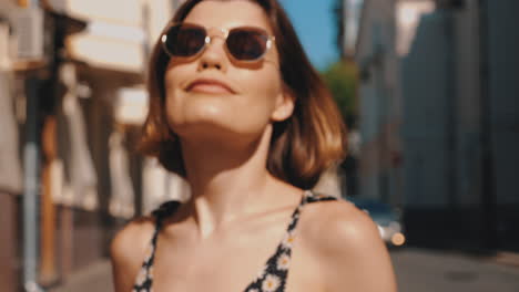 mujer elegante con gafas de sol en una calle soleada de la ciudad