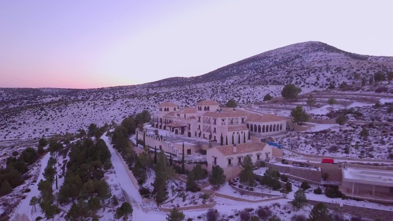 Drone panning left in the sunset of the mountains in spain with snow and of a hotel