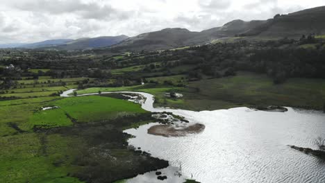 rural scene with meadows and lake and river surrounded with hills