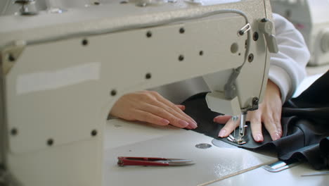 seamstress adjusts the sewing machine to work. young seamstress adjusts the sewing machine to work. hands close up