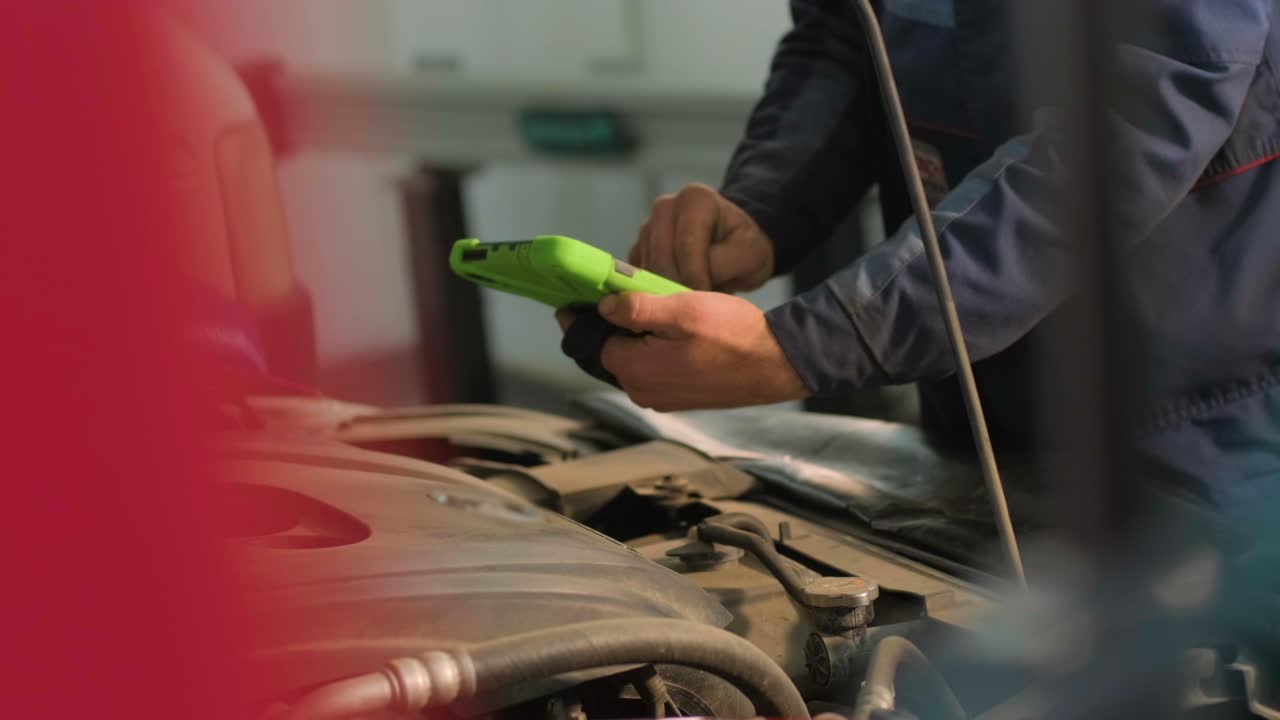 el electricista o mecánico de servicio de automóviles utiliza una tableta con software de diagnóstico interactivo futurista. inspeccionando el vehículo para encontrar componentes rotos en el compartimento del motor del automóvil moderno