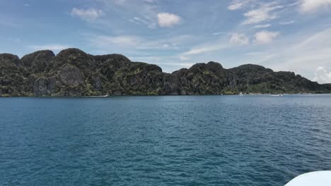 Tropeninsel-Koh-Phi-Phi-Mit-Einer-Fährfahrt-Und-Thailändischer-Flagge,-Die-Im-Wind-Weht-Und-Sich-Dem-Land-Nähert,-Thailand