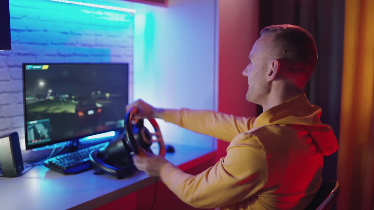 Young gamer driving the steering wheel of a racing simulator. Happy man enjoying car racing video game with a wheel. Computer simulation.