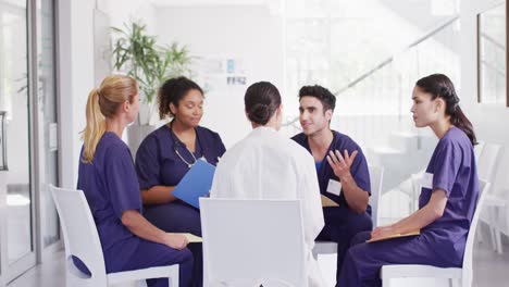 video of diverse group of male and female doctors sitting in discussion in hospital meeting