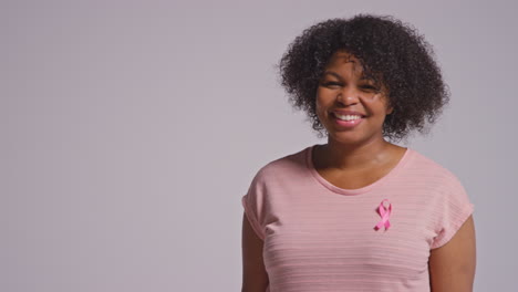 Studio-Portrait-Of-Smiling-Mid-Adult-Woman-Wearing-Pink-Clothing-And-Breast-Cancer-Awareness-Ribbon-Against-White-Background-1