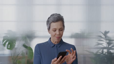 portrait-pensive-senior-business-woman-using-smartphone-in-office-enjoying-texting-browsing-online-messages-sending-emails-on-mobile-phone-slow-motion