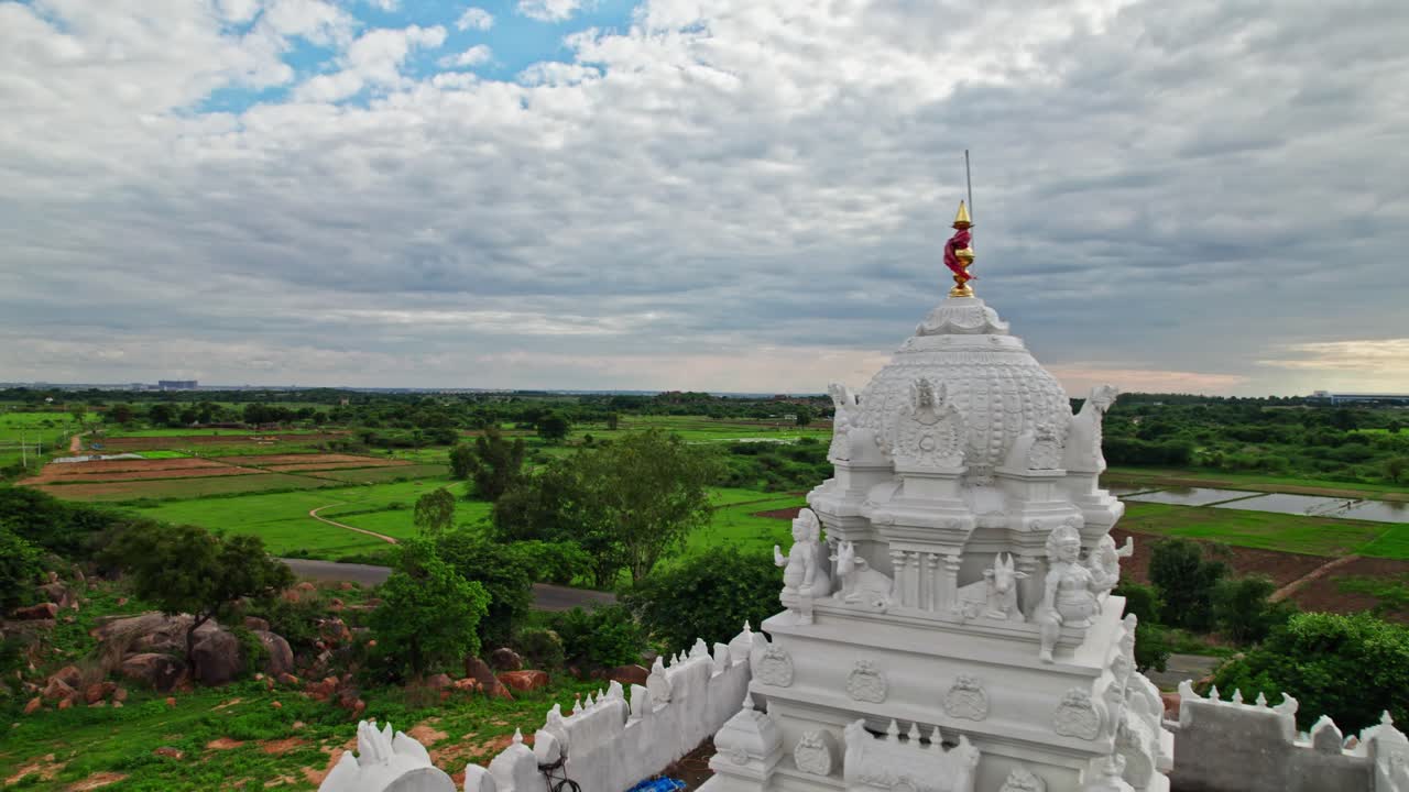 Crop fields lands with clouds, sky and temple dome, day time, push back, drone shot, 4k.