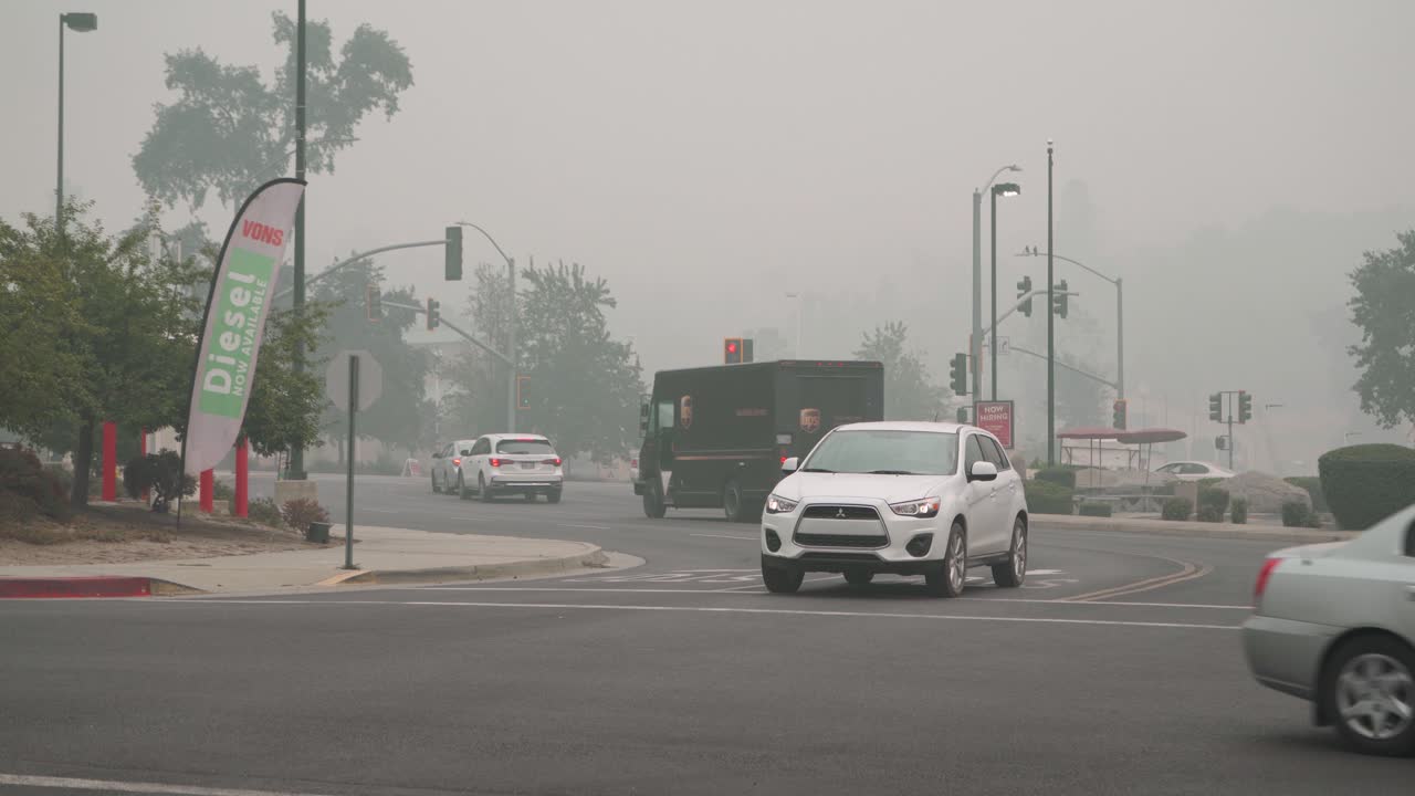 Cars drive through intersection of smoky town, creek fire, california