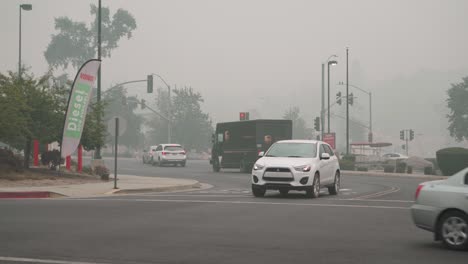 cars drive through intersection of smoky town, creek fire, california