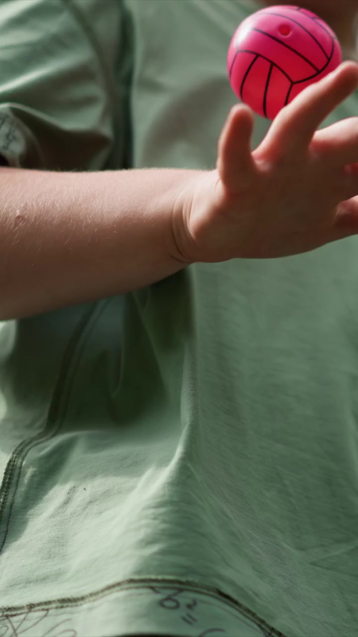 Close up of young person light green t shirt sleeve. Subject adjusts posture while wearing pale green shirt. Indoor scene lit softly focusing solely on subject upper body