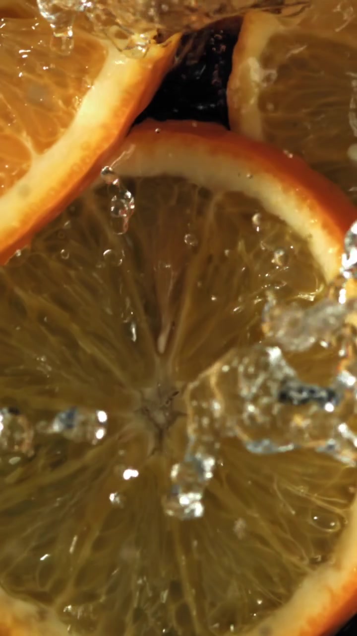 Acqua che schizza su vivaci fette d'arancia al rallentatore.