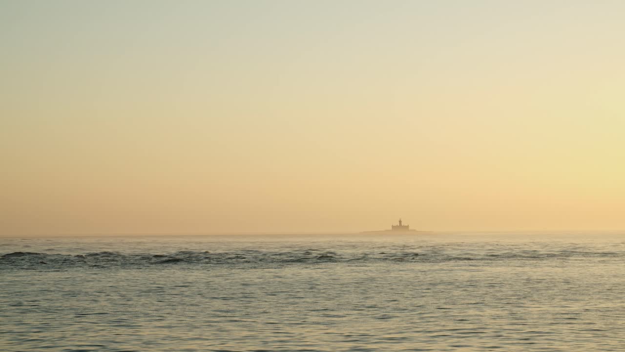 一艘船在海中日落时的灯塔景色