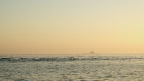 Vista-De-Un-Faro-Desde-Un-Barco-En-Medio-Del-Mar-Al-Atardecer