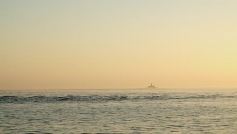 vista de un faro desde un barco en medio del mar al atardecer