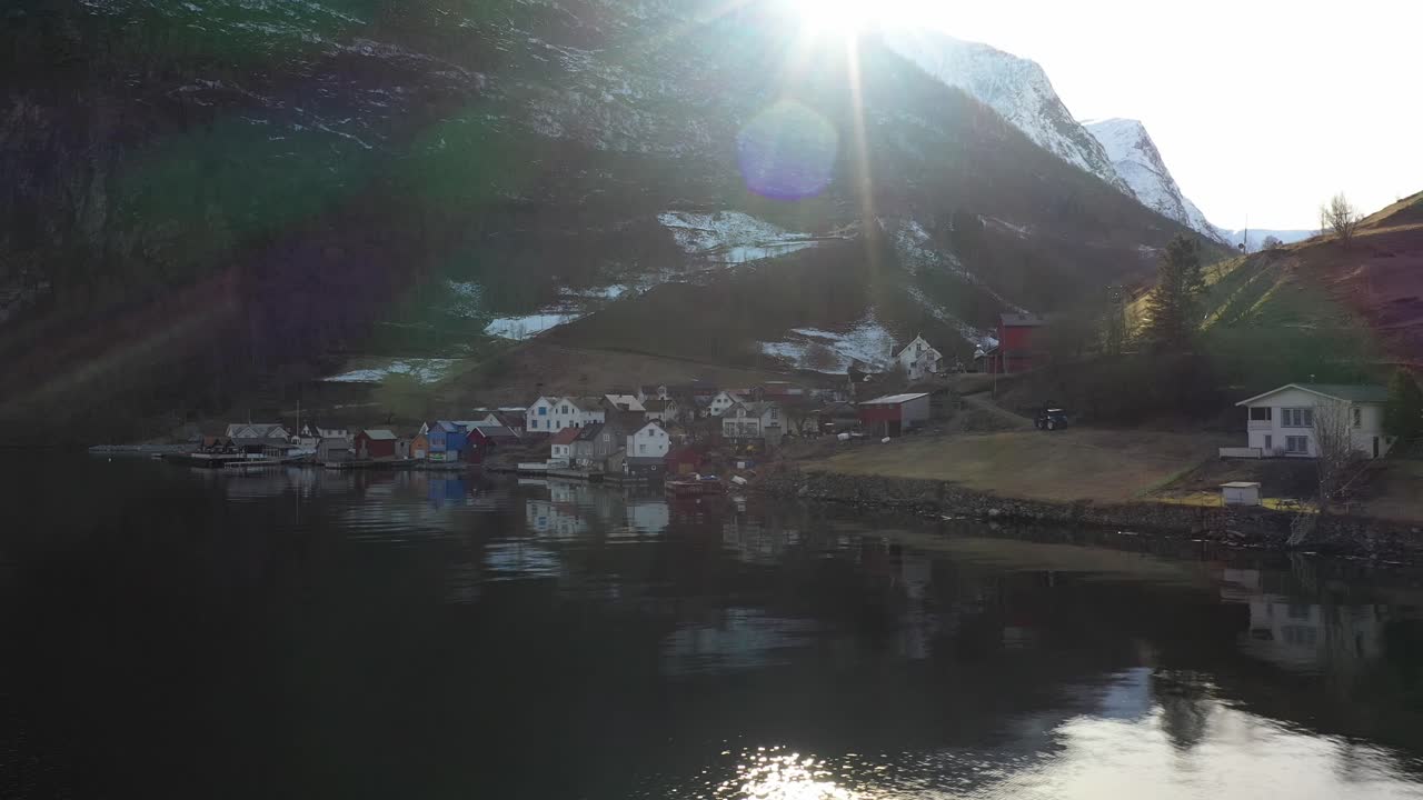 이른 아침 일출 동안 언드레달 마을을 보여주는 저고도 공중 도시 - 산봉우리와 산골짜기 배경 위에 태양이 있는 해변에서 볼 수 있습니다.