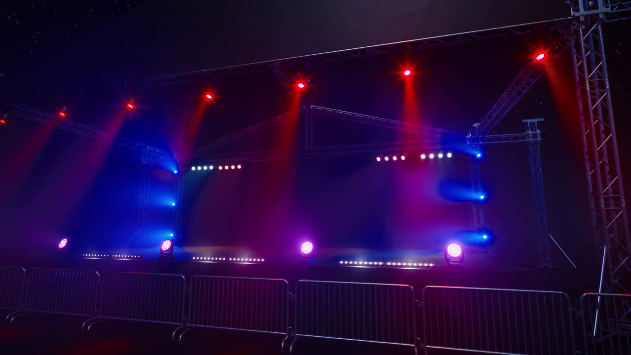 Outdoor stage set up for concert with vibrant lighting and barriers