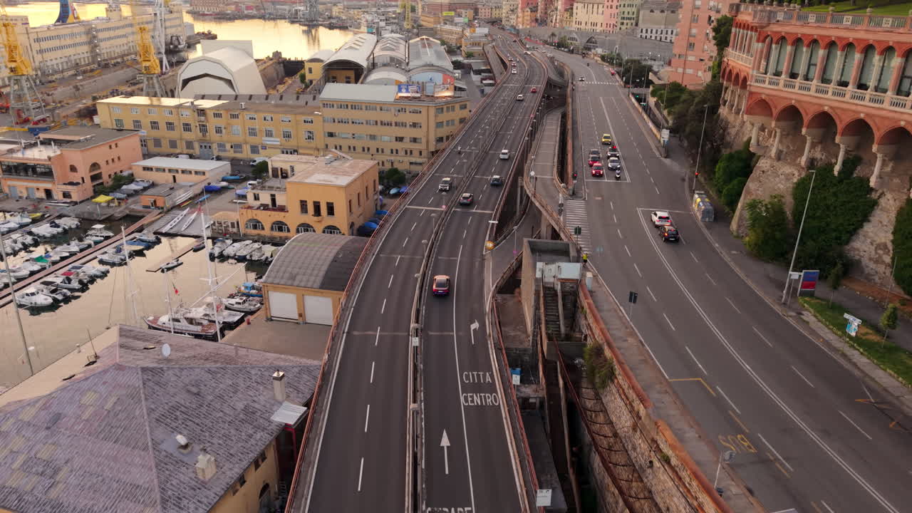 Drone shot of Genoa port in Italy with highway, cars, boats and city buildings at sunset