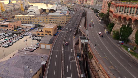 drone shot of genoa port in italy with highway, cars, boats and city buildings at sunset