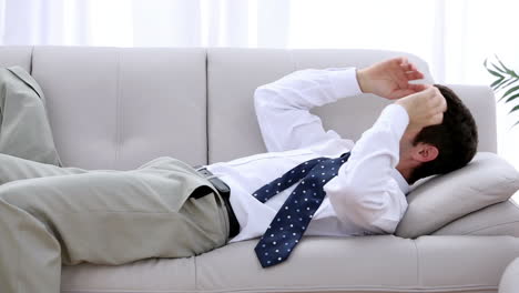 businessman crashing down onto sofa