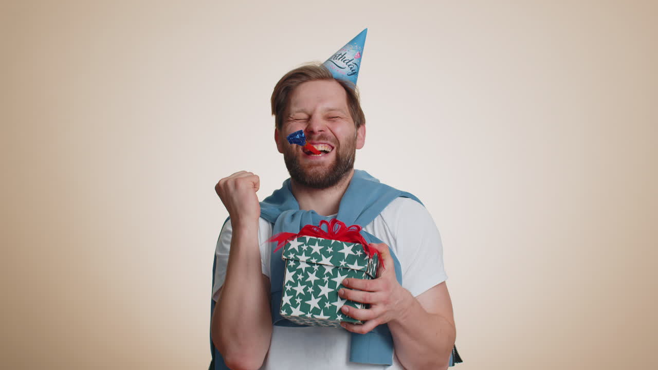 행복하고 흥분한 행운의 남자가 생일 모자를 입고 파티 성공을 축하하고 승리를 얻습니다.