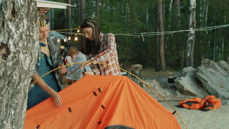 hombre joven y mujer montando una tienda en el campamento